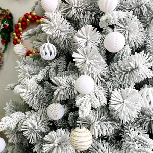 Vue détaillée de boules de Noël en velours blanc et or sur une branche de pin