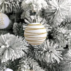 Détail d'une boule de Noël blanche avec rayures dorées pailletées et attache argentée