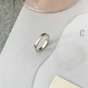Macro detail of silver ring featuring modern vertical striped texture and polished finish