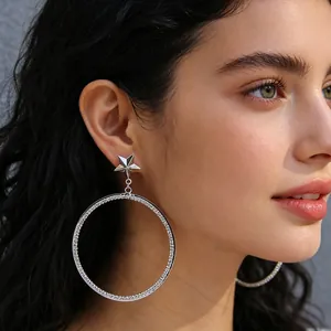 Fashionable silver star hoop earrings with sparkling rhinestones worn by a model