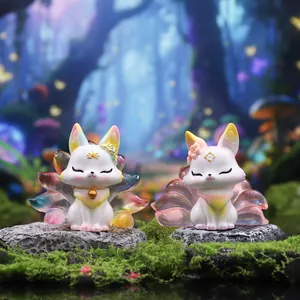 Close-up of two Nine-Tailed Fox resin figurines with gradient tails on mossy stone