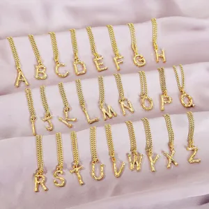 Golden A-Z initial necklaces with bamboo texture on silk fabric background