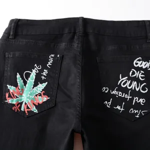 Men's slim black stretch jeans featuring street-style skull and leaf graphic prints on back pockets
