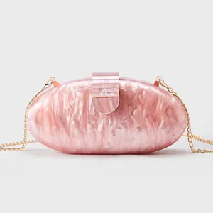 Detail of pink marble acrylic evening clutch with gold chain and shell texture