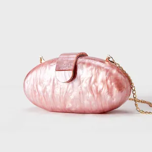Macro view of shell-textured acrylic clutch with marble pattern and golden metal chain