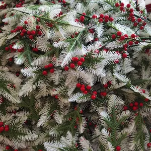 Dettaglio di rami di pino artificiali con neve e bacche rosse per decorazioni natalizie