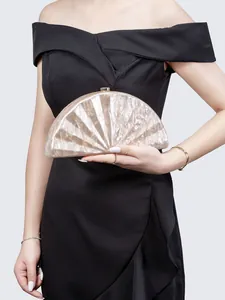 Detail of a pearl white marble acrylic half-moon clutch held against a black dress