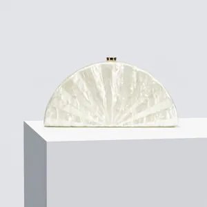 Detail view of pearlescent white acrylic fan-shaped evening clutch with gold metal clasp