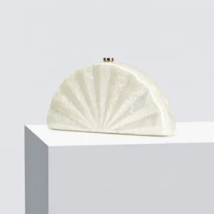 Detail of white marble acrylic evening clutch with fan shape and gold metal clasp