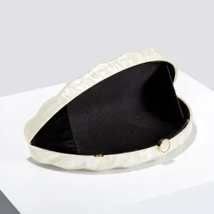 Detail of pearl white marble acrylic shell clutch with gold clasp and black lining