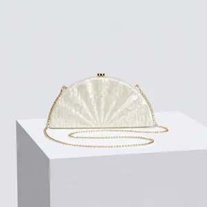 Detail of ivory acrylic fan-shaped evening clutch with pearlescent finish and gold chain