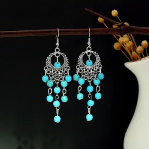 Détail de boucles d'oreilles bohèmes argentées avec perles turquoise sur une branche