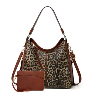 Close-up of leopard print tote bag set featuring brown faux leather trim and gold zippers