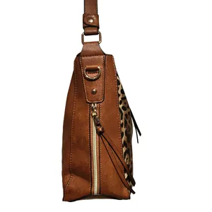 Detail of brown faux leather tote with leopard print panels and tassel zippers