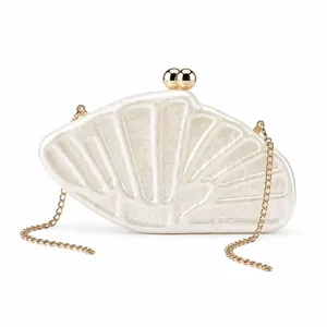 Détail d'un sac de soirée en acrylique en forme de coquille blanche avec chaîne dorée