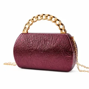 Detail of wine red metallic snakeskin evening bag with gold chunky chain handle