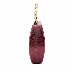 Detail view of burgundy faux leather clutch with gold chain handle and crackle texture