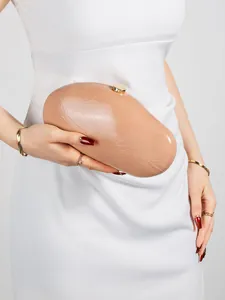 Macro view of a nude oval clutch bag featuring glossy pleated leather and golden clasp