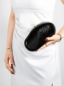 Detail of elegant black patent leather evening clutch with gold metal clasp for gala events