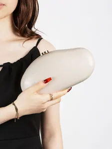 Macro detail of cream marble evening clutch featuring a cylindrical gold metal clasp