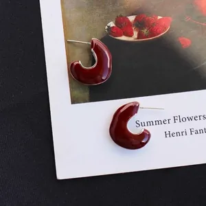 Retro deep red enamel C-shaped heart earrings on artistic vintage oil painting card