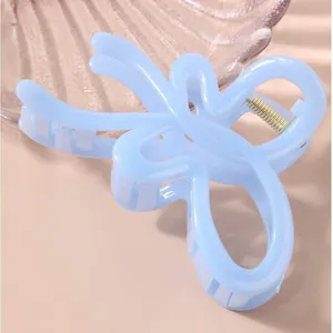 Ice blue butterfly hair claw clip with gold spring on a pink background for thick hair