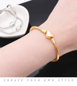 Close-up of a gold snake chain bracelet featuring a polished heart pendant on a wrist