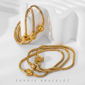 Classic gold snake bone bracelet with heart charms and crystal beads on a white display