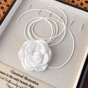 Gros plan d'un collier choker fleur de camélia en satin blanc dans un coffret cadeau chic
