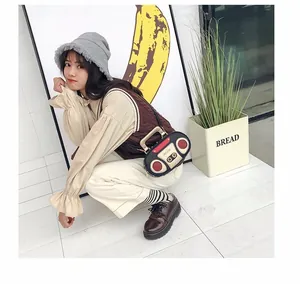 Detailed side view of vintage radio shaped crossbody bag styled with retro outfit