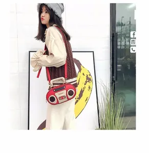 Retro red radio-shaped crossbody bag shown on model with shoulder strap details