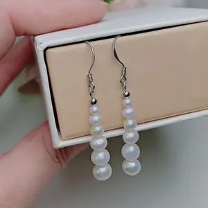 Macro shot of S925 sterling silver earrings featuring a gradient of six white pearls