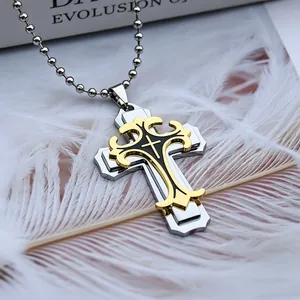 Vue macro du pendentif croix dorée superposée avec gravures et chaîne à perles argentée