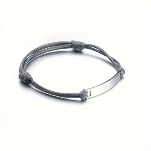 Macro detail of polished silver metal plate on adjustable grey braided rope bracelet
