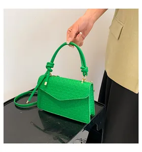Detail of green crossbody bag featuring woven geometric texture and knotted tube handles