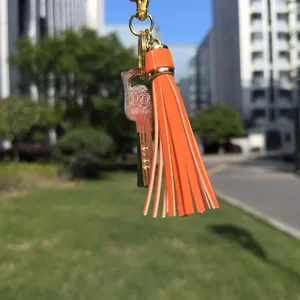 Close-up of orange leather tassel and golden key charm with LOCK engraving on keychain