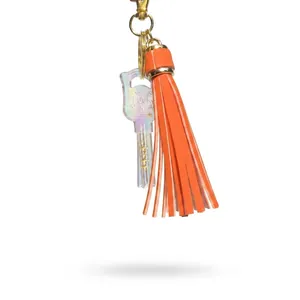 Close-up of orange leather tassel and golden key charm with LOCK engraving on keychain
