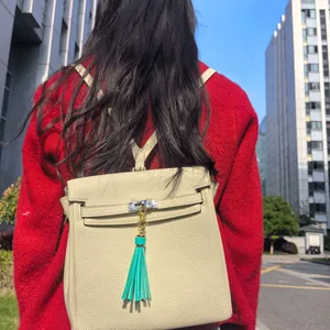 Detail of cream leather backpack with lychee grain texture and turquoise tassel charm