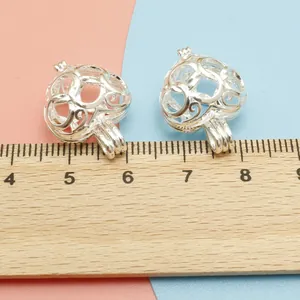 Detailed size comparison of heart-shaped hollow metal pendants on a wooden ruler