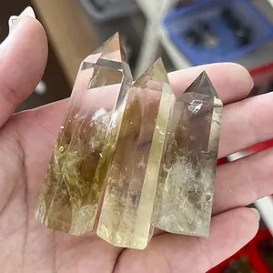 Primo piano di tre prismi esagonali in citrino naturale tenuti in mano con trama chiara