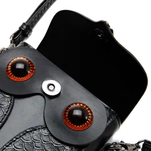 Détail du design œil de hibou sur sac bandoulière steampunk en similicuir noir et aimanté