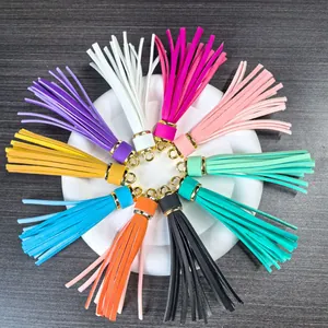 Set of ten colorful PU leather tassel keyrings with golden metal caps on a white stand