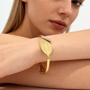 Elegant gold leaf open bangle with pavé zircon accents shown on a model's wrist