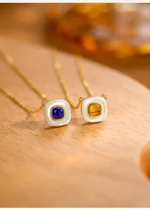 Detail von Lapislazuli und Bernstein Anhängern mit Goldketten auf einem Holztablett
