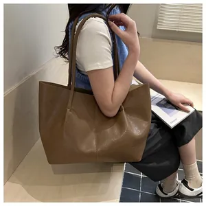Detailansicht der karamellfarbenen Ledertasche mit vertikalen Nähten und langen Trägern