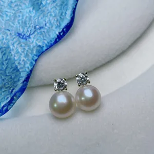 Macro view of white freshwater pearl earrings with sparkling stones on S925 silver studs