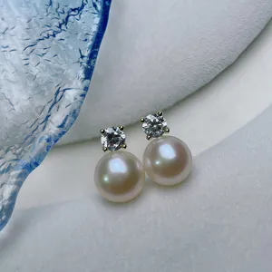 Macro view of freshwater pearl stud earrings with sparkling round gemstone in gold setting
