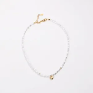 Detail of white rice pearl necklace with a gold heart pendant and lobster clasp