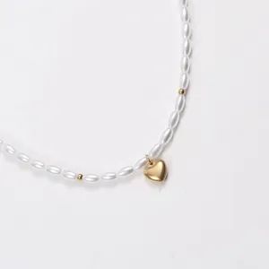 Detailed macro view of rice-shaped pearl necklace with gold heart-shaped pendant