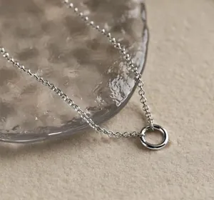 Detailed macro view of minimalist geometric gold circular pendant with fine link chain